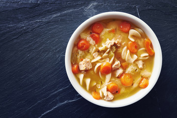 top down photo of chicken noodle soup with copy space on slate