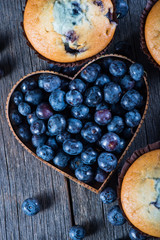 Blueberry muffins and fruit heart on wooden table from above
