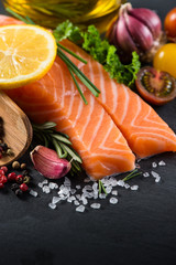 Portion of fresh salmon with spices,herbs and vegetables on blac