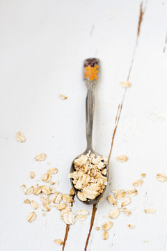 One tablespoon of oatmeal is a white wooden background.