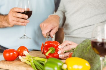 Mature couple having red wine while making dinner