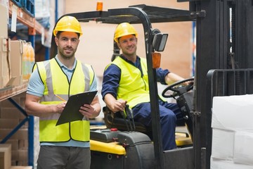 Smiling warehouse worker and forklift driver - obrazy, fototapety, plakaty