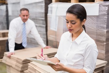 Warehouse manager writing on clipboard