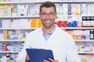 Happy pharmacist writing on clipboard