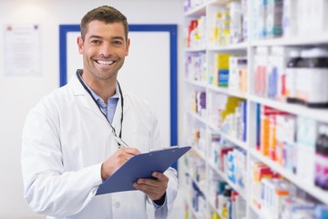 Handsome pharmacist writing on clipboard