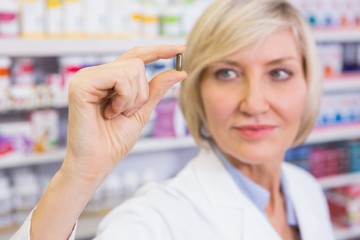 Blonde pharmacist in lab coats showing pill