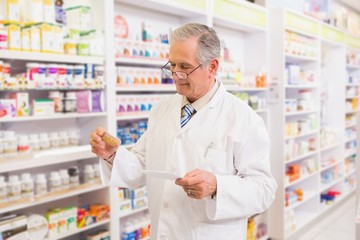 Senior pharmacist looking at medicine and prescription