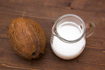 Coconut milk in jug on wooden table seen from above