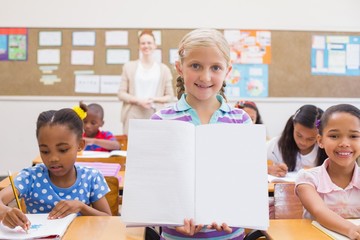 Cute pupil smiling at camera during class presentation