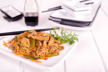 Dish of rice spaghetti, mushrooms and meat on a white plate