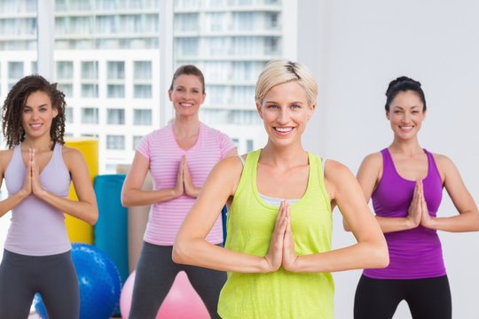Women with hands joined exercising at gym