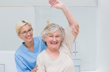 Senior patient being assisted by nurse in raising arm