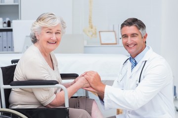 Obraz premium Happy doctor holding senior patients hands