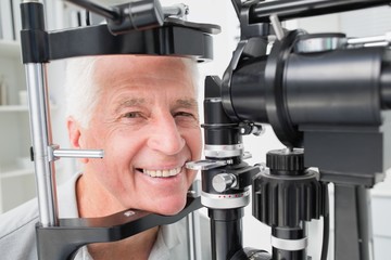 Senior patient using slit lamp at clinic