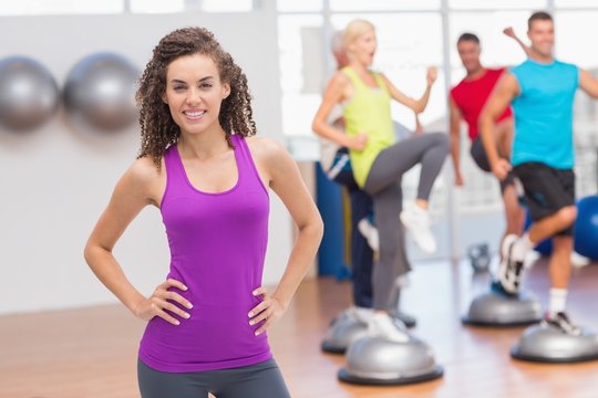 Happy fit woman standing hands on hips at gym