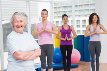 Fototapeta premium Senior woman with arms crossed standing in gym
