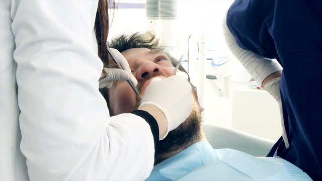 Closeup of man being checked by dentist