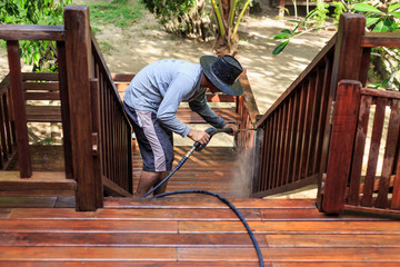 Thai man do a pressure washing on timber