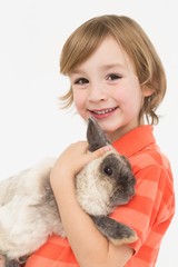 Naklejka premium Portrait of happy boy holding fluffy rabbit