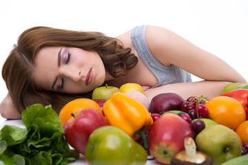 Portrait of a young woman sleeping on the table with many fruits