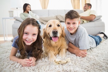 Siblings lying with dog while parents relaxing on sofa
