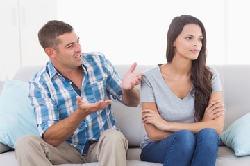 Man arguing with angry woman on sofa