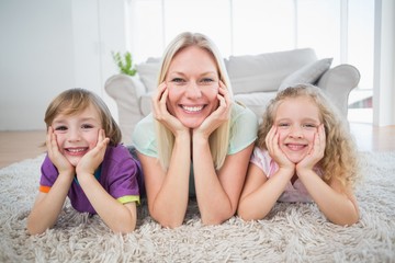 Mother and children with head in hands lying on rug