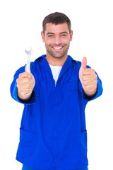 Smiling mechanic holding spanner while gesturing thumbs up