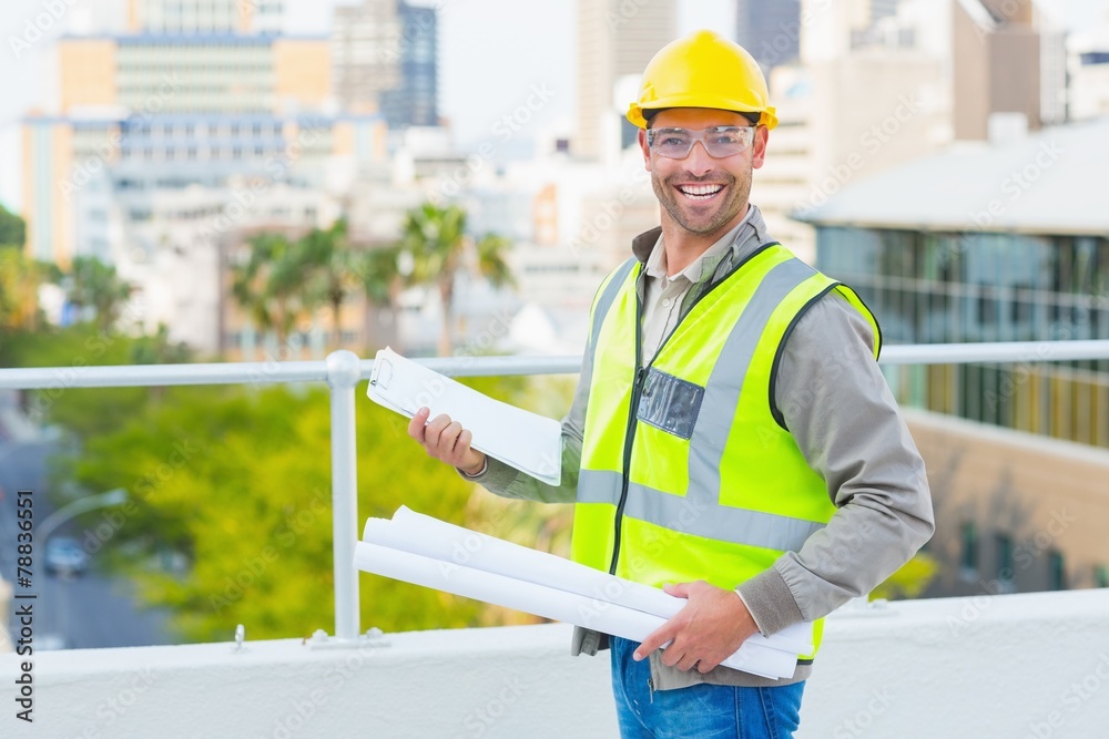 Poster smiling male architect with blueprints and clipboard