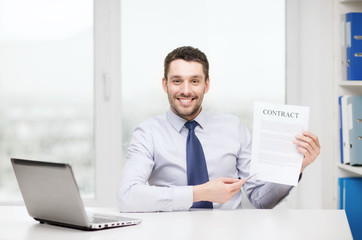 businessman with laptop and contract at office