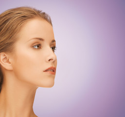 Fototapeta premium beautiful young woman face over violet background