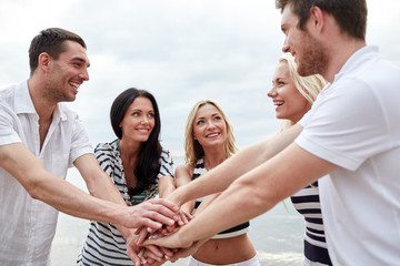 smiling friends putting hands on top of each other