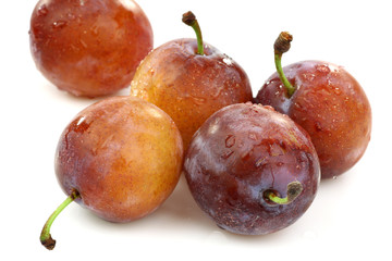 five fresh ripe plums on a white background