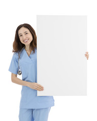 Smiling friendly female doctor or nurse showing a blank white bi