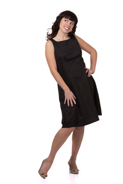 Smiling woman standing in a black dress and looking to the side.