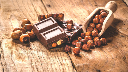 Milk chocolate with nuts on a wooden spoon in a country style.