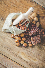 milk chocolate with hazelnuts and walnuts in a sack on a wooden