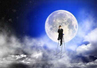 Boy in suit stands on a step-ladder against the background of a