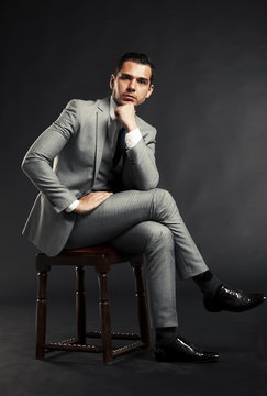 Portrait Of A Handsome Man Sitting In The Armchair Over Black 