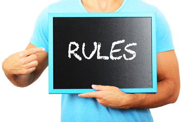 Man holding blackboard in hands and pointing the word RULES