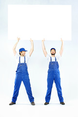 Obraz premium Two handsome builders holding a board