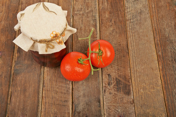 Conservation, tomato and notebook with pencil wooden background