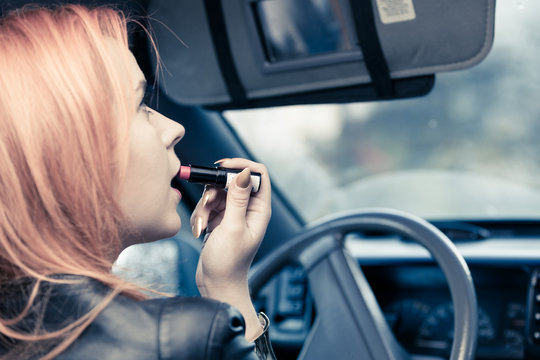 girl painting her lips doing make up while driving the car.