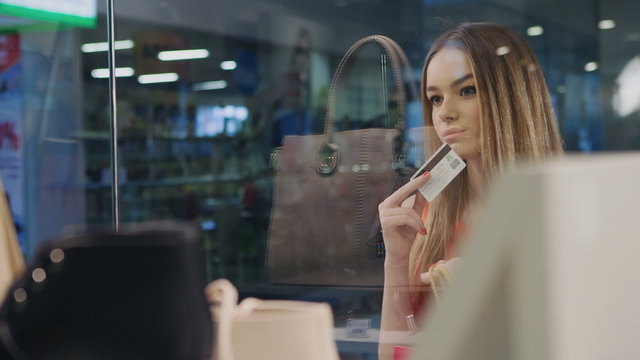 Girl with credit card in hand at the storefront saw the product