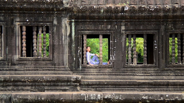 Zoom Out Female Buddhist Meditating in Window - Angkor Wat, Cambodia