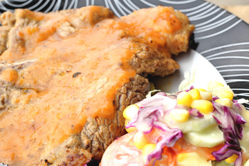 Steaks, french fries with vegetables salad on a plate.