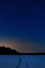 Naklejka premium Snow-covered road on the background of the starry night sky.