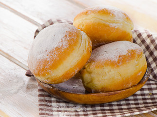 Sweet homemade Donuts with powdered sugar on  wooden plate.