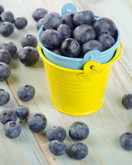 Blueberries in  small buckets on a wooden table.