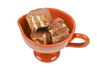 Pieces of chocolate sponge cake in a ceramic bowl isolated on wh